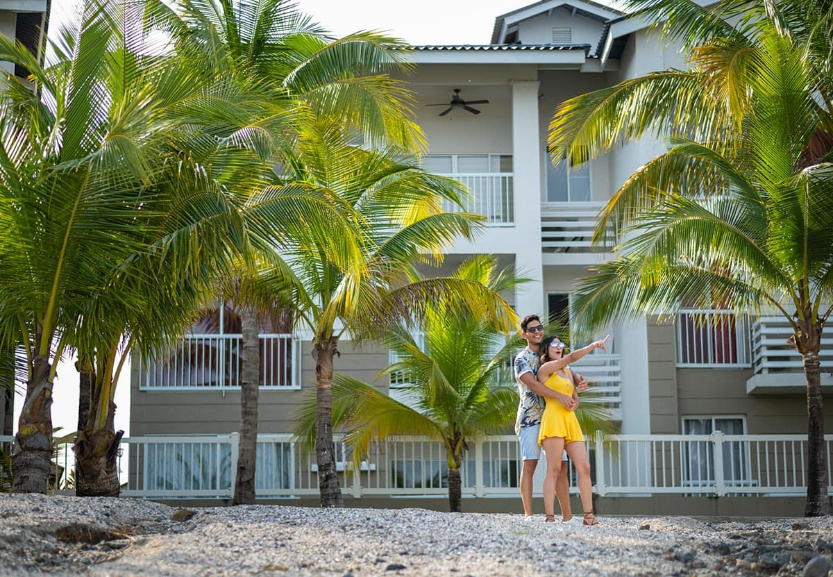 Playa Dorada apartment building framed by palm trees with residents on the walkway