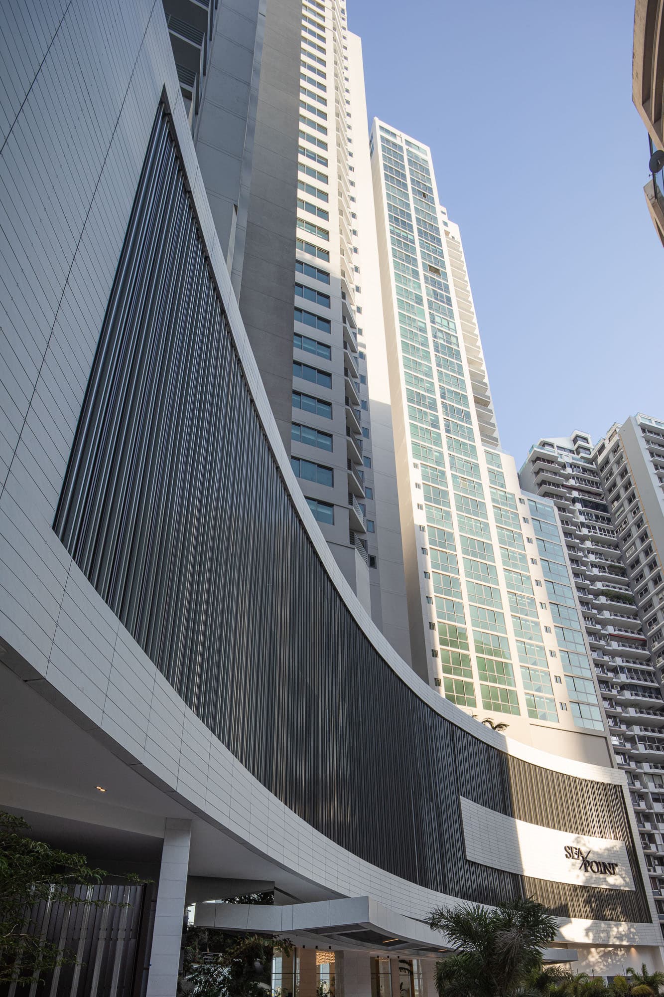 Curved white podium and glass tower of Sea Point seen from street level in Punta Paitilla