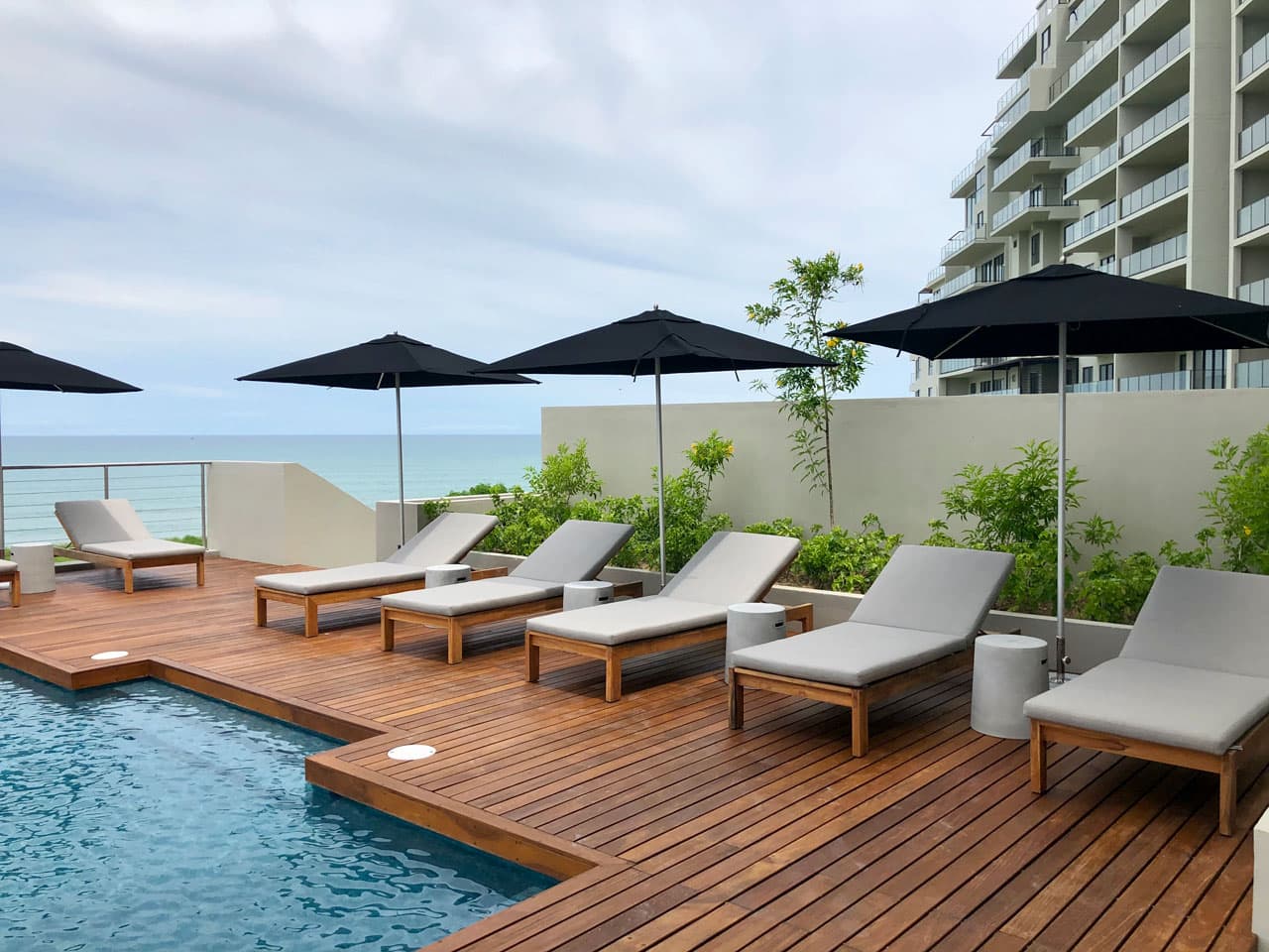 Wooden pool deck with umbrellas and ocean views at Solaria