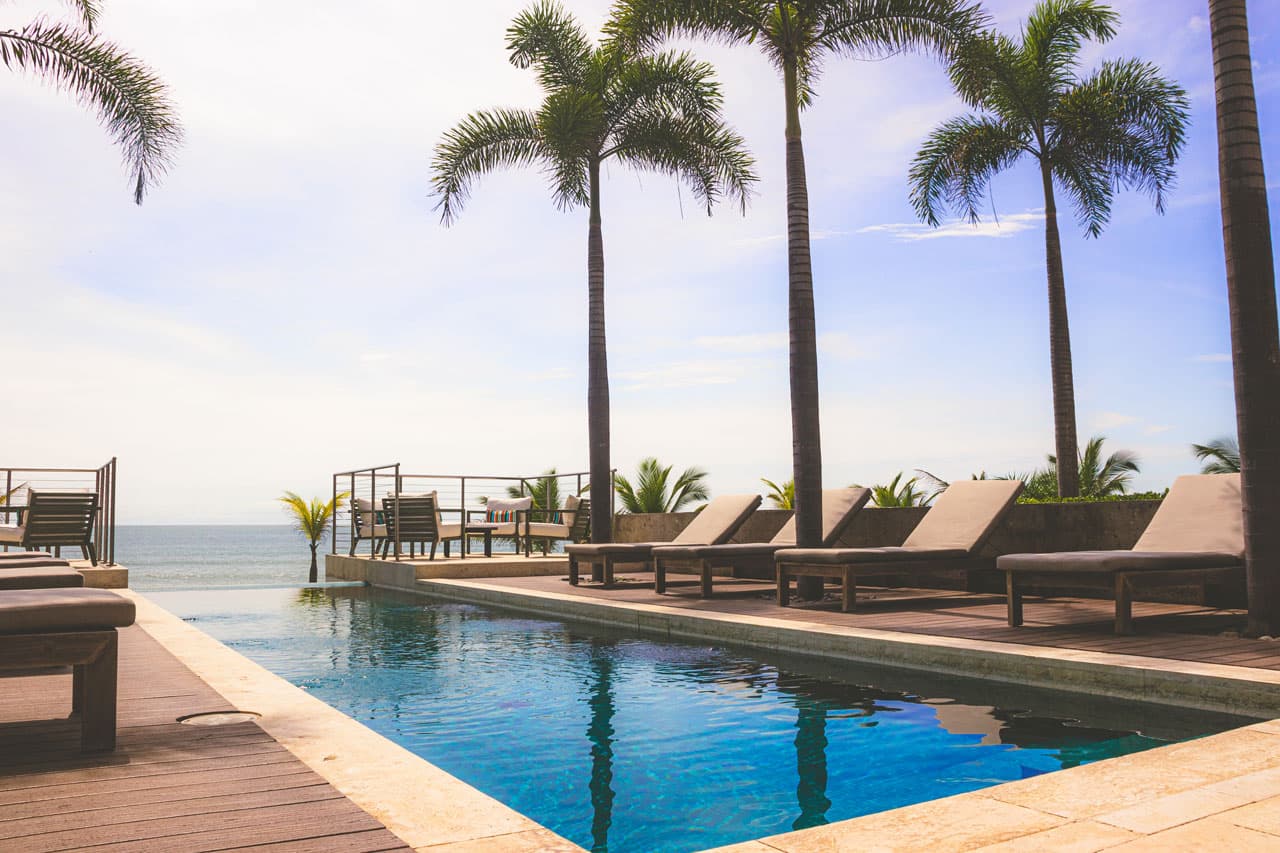 Pool deck with sun loungers facing the sea at Punta Caelo