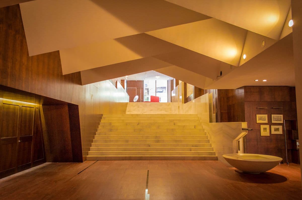 Double-height lobby with a stone staircase and wood-paneled walls at The Palace
