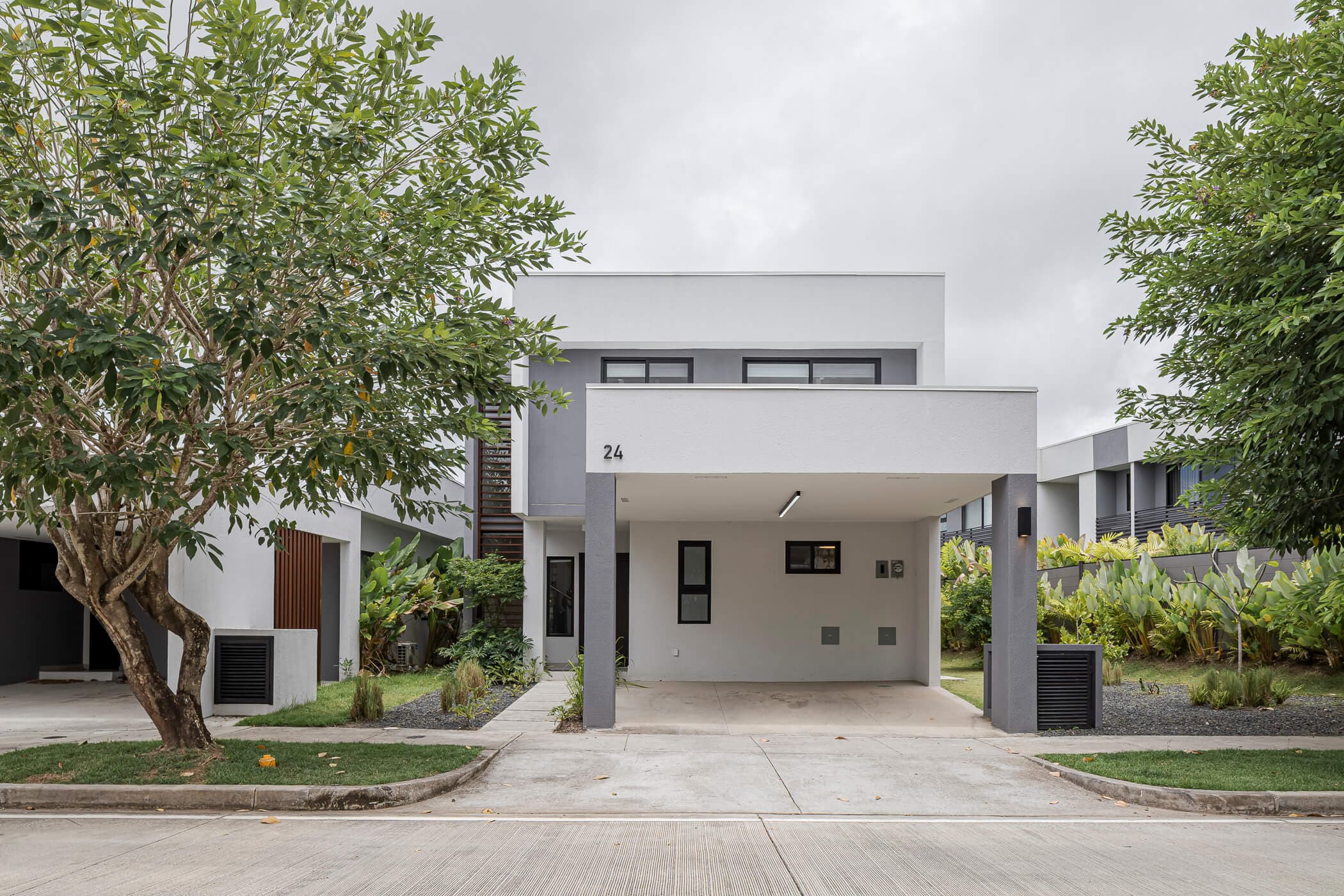 Imaterra house facade with covered carport and mature trees