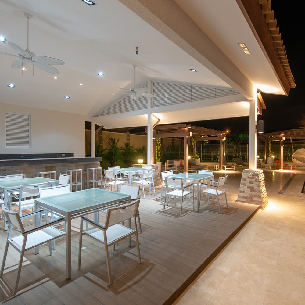 Covered terrace bar with tables at Bosques del Pacifico, lit at dusk