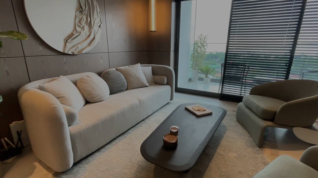 Living room with curved sofa and floor-to-ceiling windows in the NEXT model apartment, Coco del Mar