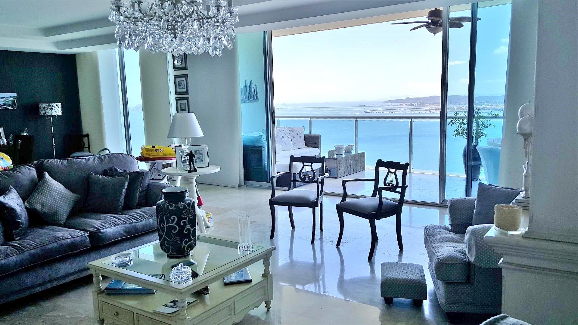 Photograph of a furnished living room opening onto the ocean-view balcony in an Aquamare apartment