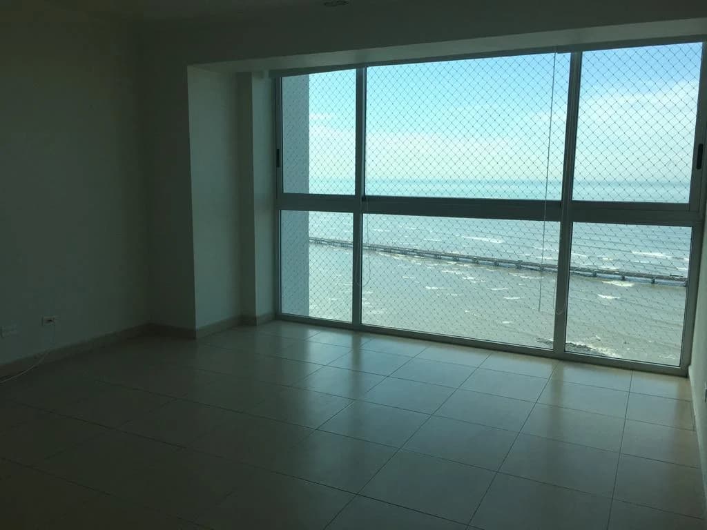Empty living area of a Nautica apartment with full-height ocean-view windows