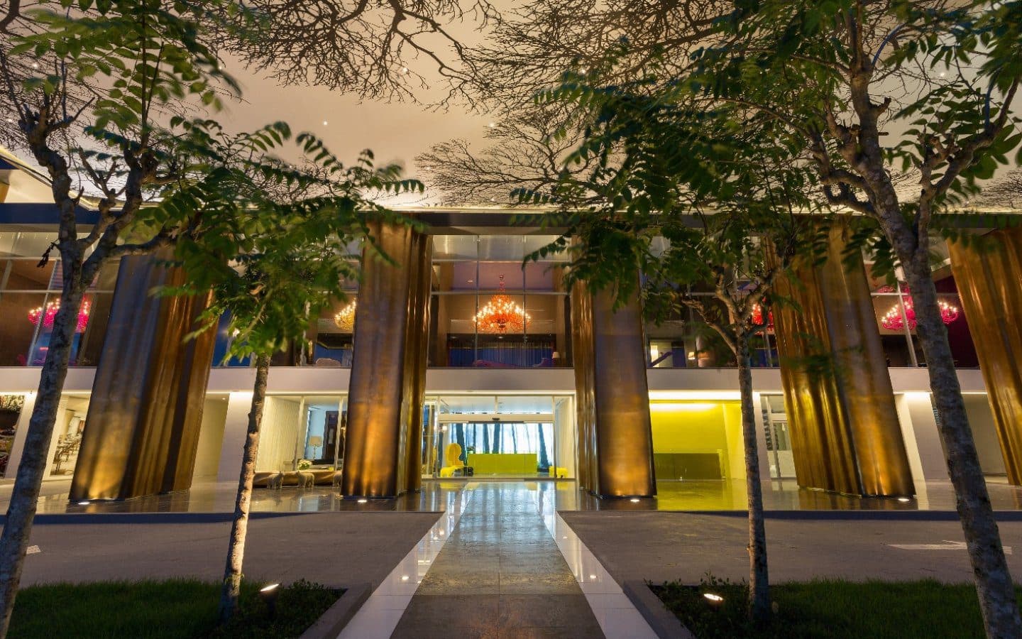 Tree-lined entrance walkway to the lobby of Yoo Panama & Arts Tower at dusk