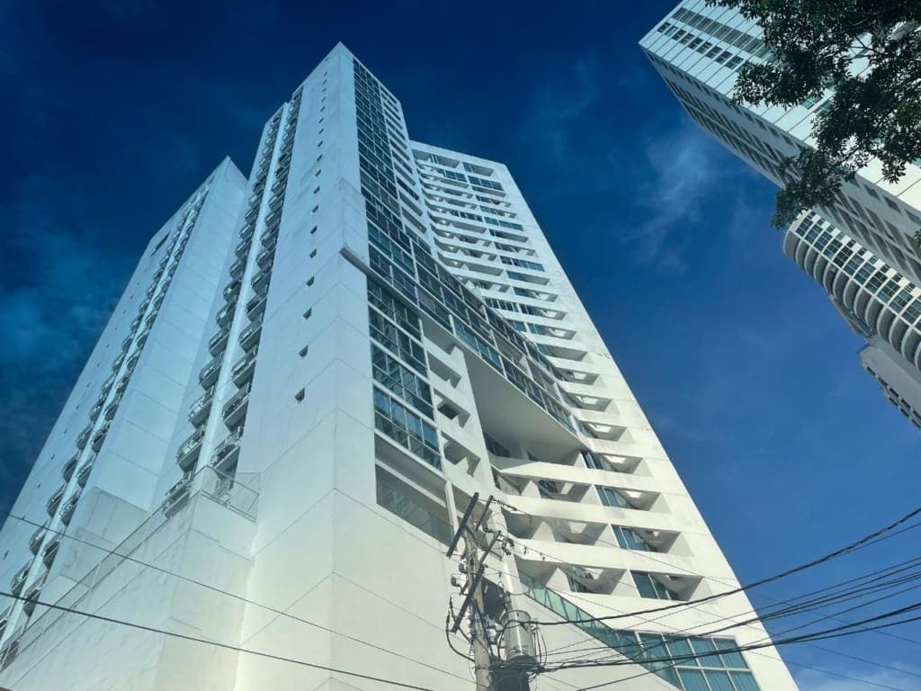 Low-angle view of the PH Infinity residential tower against a blue sky, San Francisco, Panama City