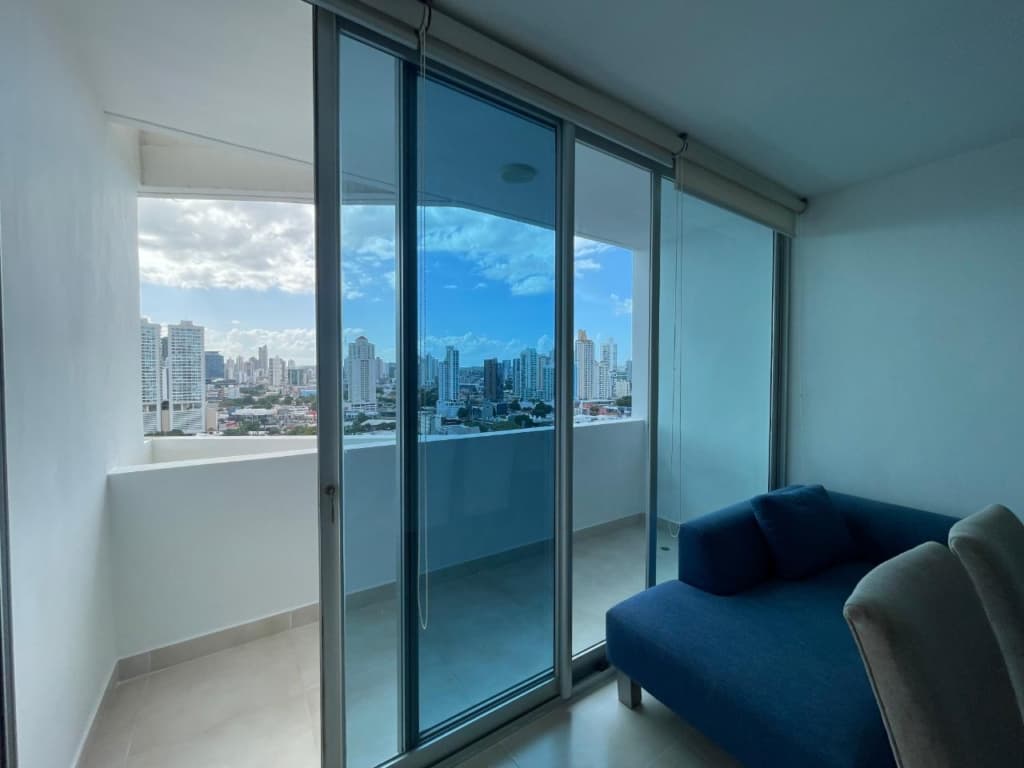 Living area with glass doors to a balcony overlooking the skyline at PH Infinity, San Francisco, Panama City