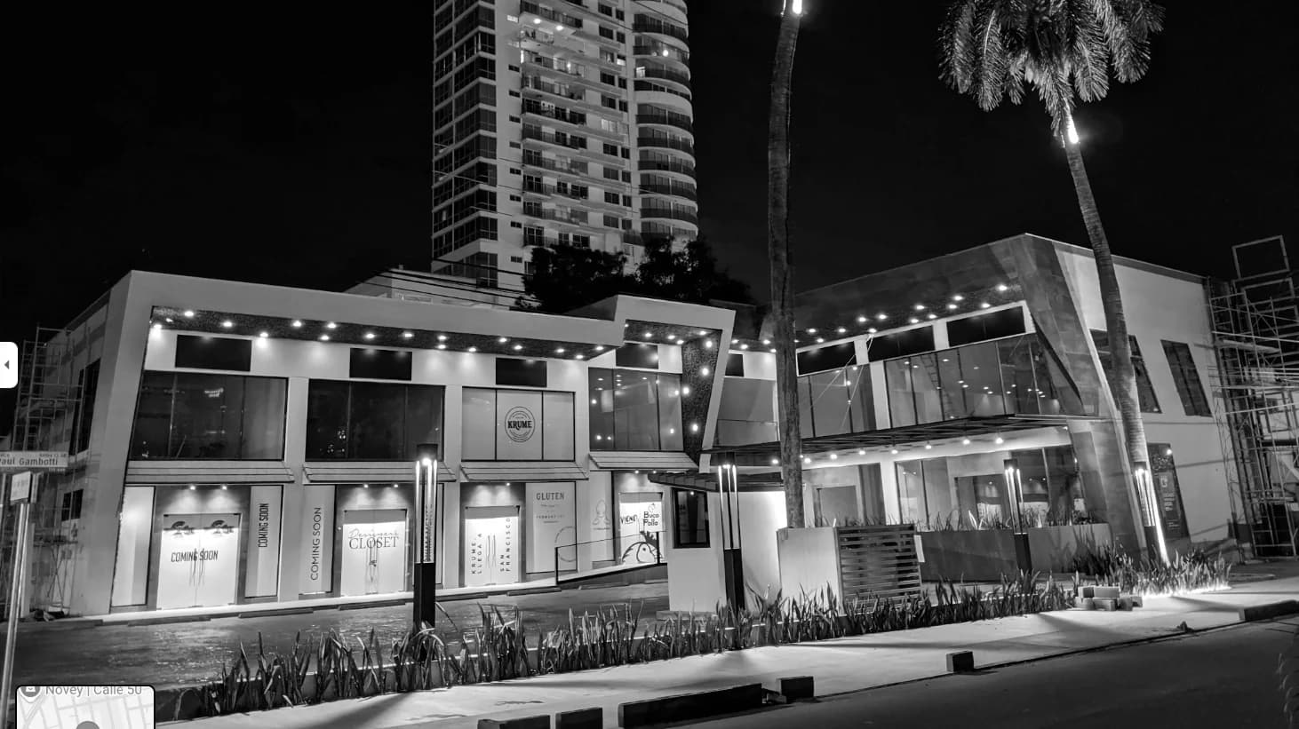 Black-and-white night view of the illuminated storefronts at Plaza Corner 68, San Francisco, Panama City