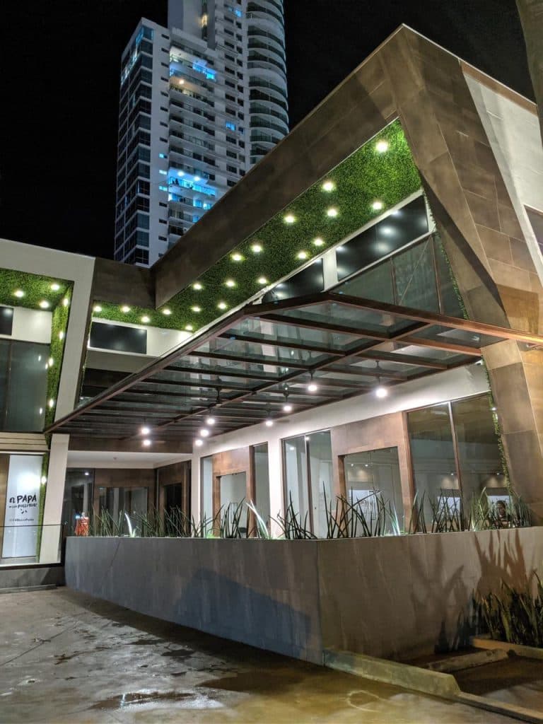 Night view of the Plaza Corner 68 corner canopy with its green wall and lit storefronts, San Francisco, Panama City