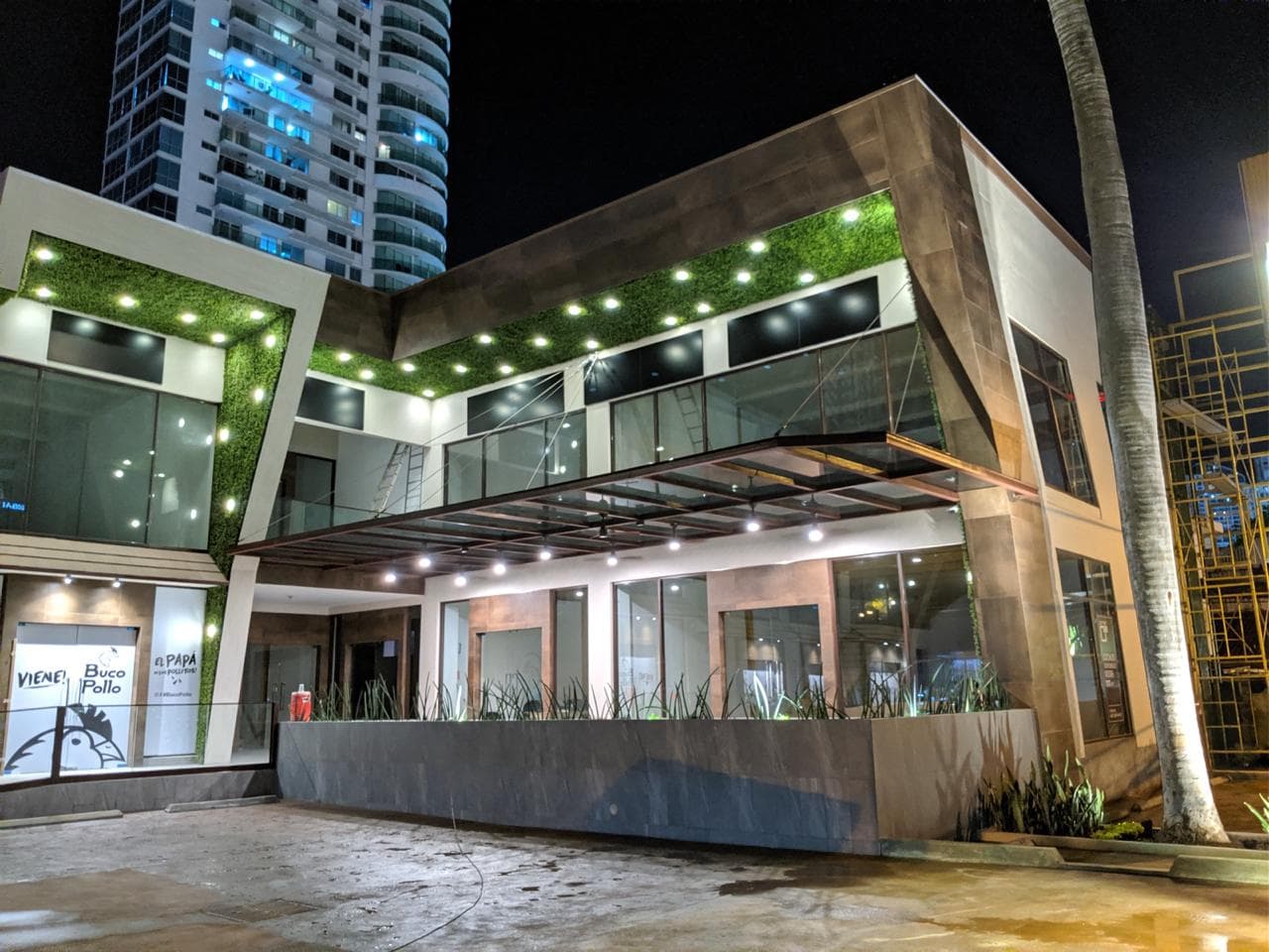 Illuminated terrace and glass storefronts under the angled canopy of Plaza Corner 68, San Francisco, Panama City