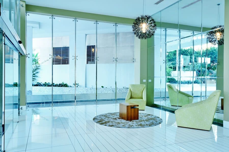 Glass-walled lobby lounge with green armchairs at Q Tower, Punta Pacifica