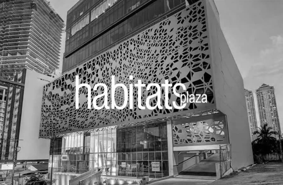 Black-and-white view of the Habitats Plaza office building with its perforated metal facade and name sign, Panama City