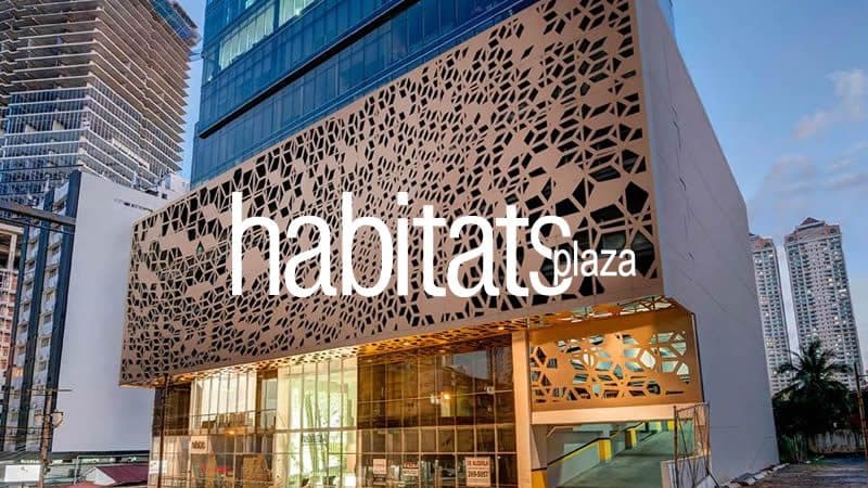 Habitats Plaza office building with its copper-toned perforated facade and name sign at dusk, Panama City