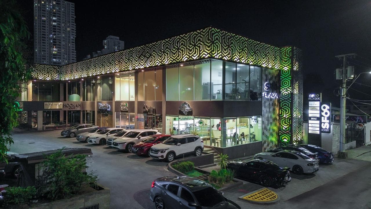 Night view of SF 69 Plaza with its lit lattice facade and full parking lot, San Francisco, Panama City