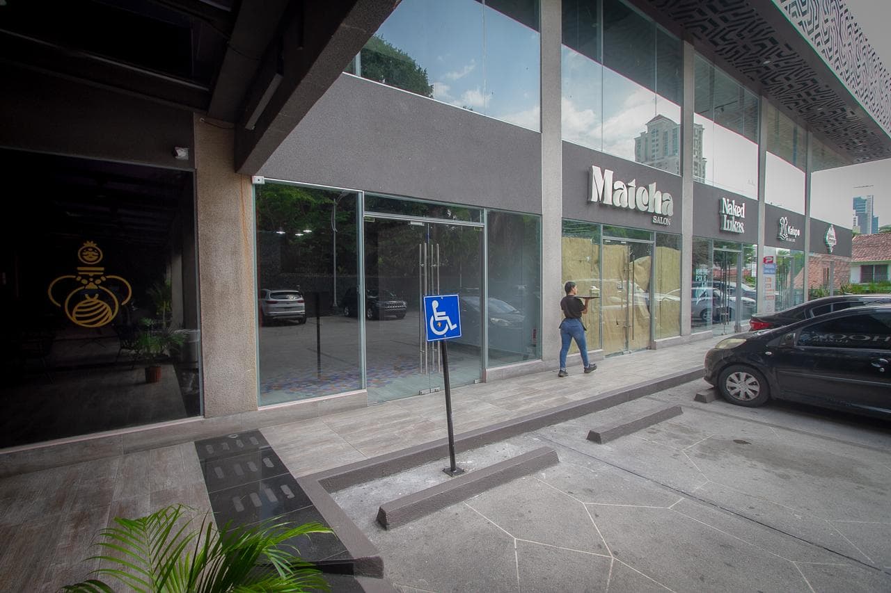 Ground-floor walkway with glass storefronts and accessible parking at SF 69 Plaza, San Francisco, Panama City