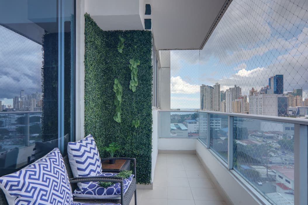 Balcony with a green wall and patterned armchairs overlooking the city at Harmony Tower, San Francisco, Panama City
