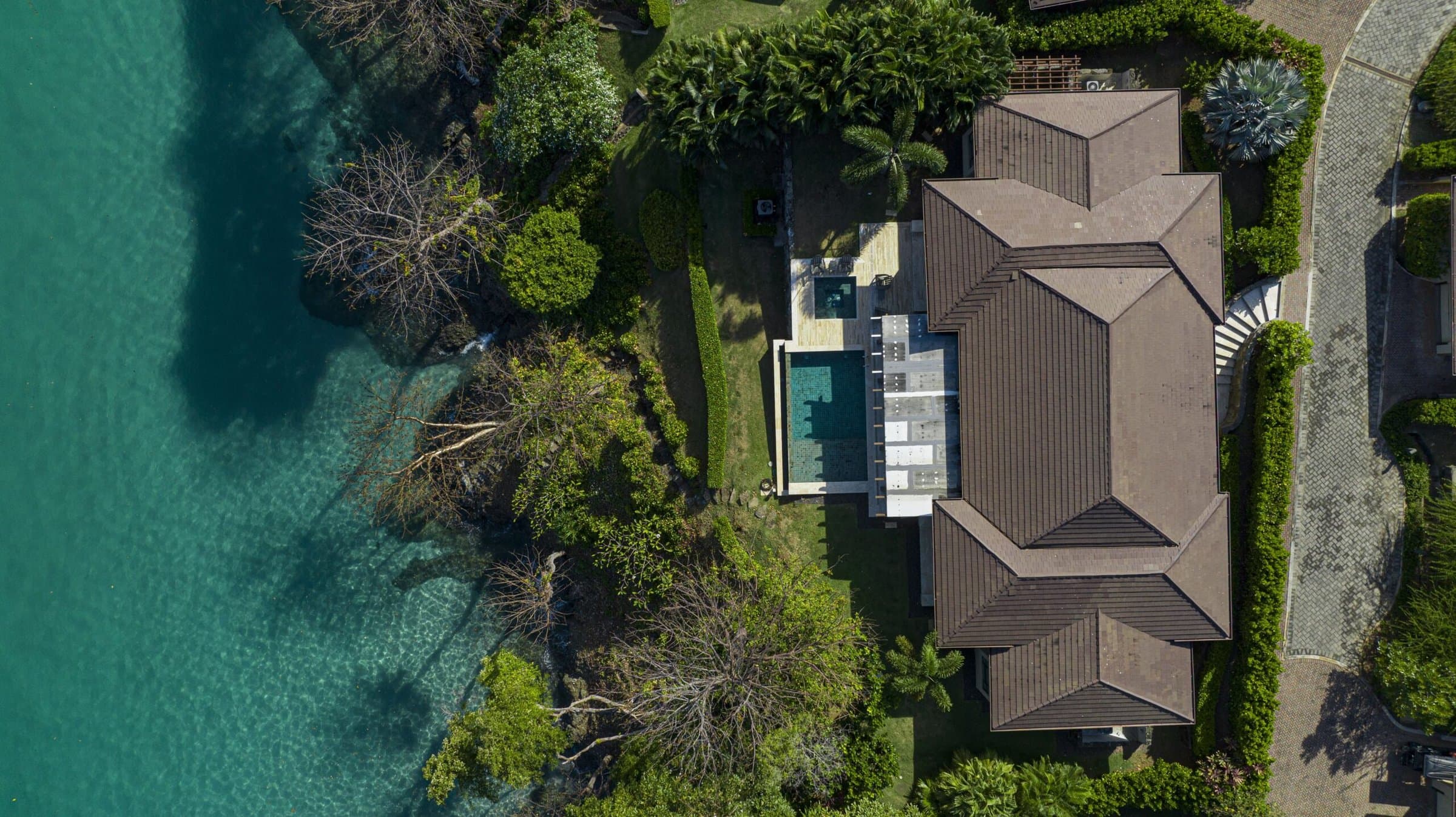 Top-down aerial of a La Peninsula Villa with its pool beside the sea on Pearl Island