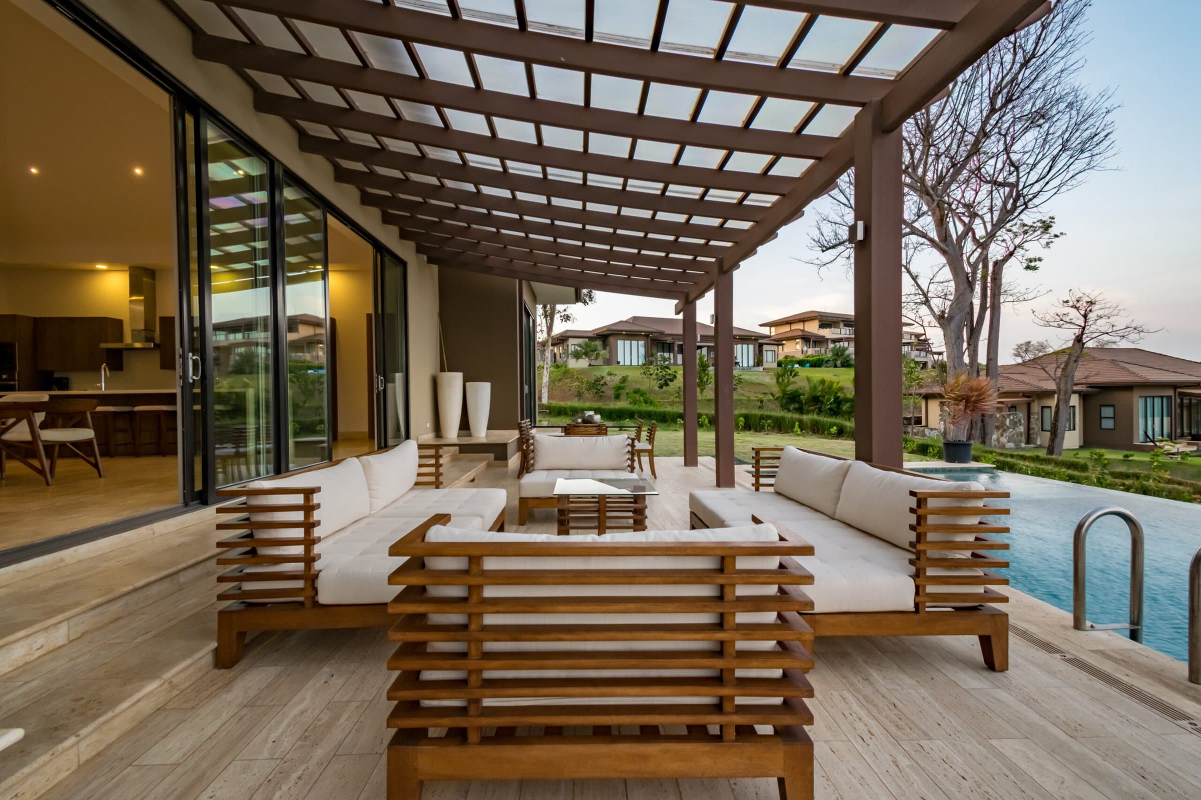 Outdoor lounge under a pergola beside the pool of a La Peninsula Villa