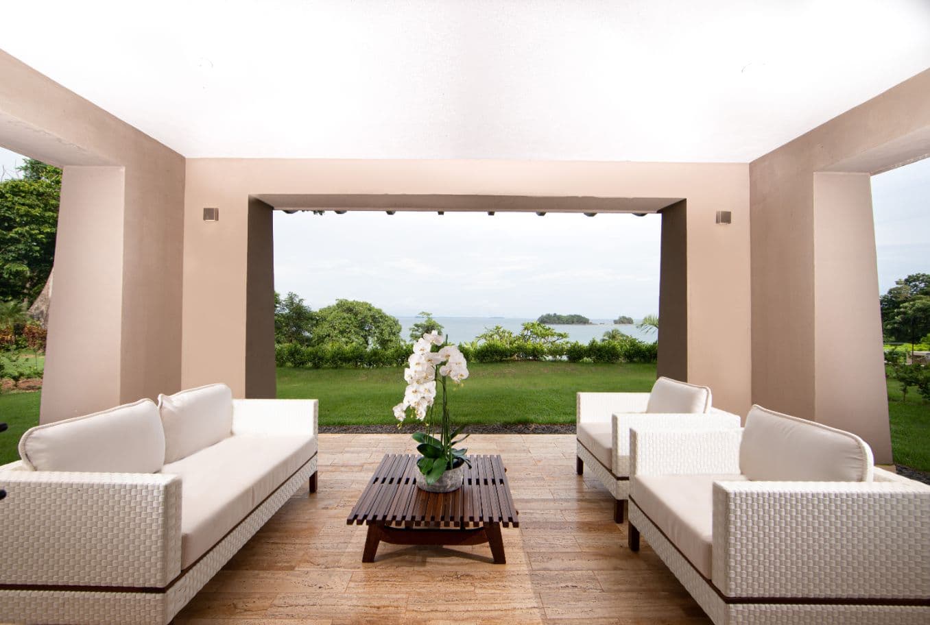 Open-air living room framing lawn and ocean views at a La Peninsula Villa