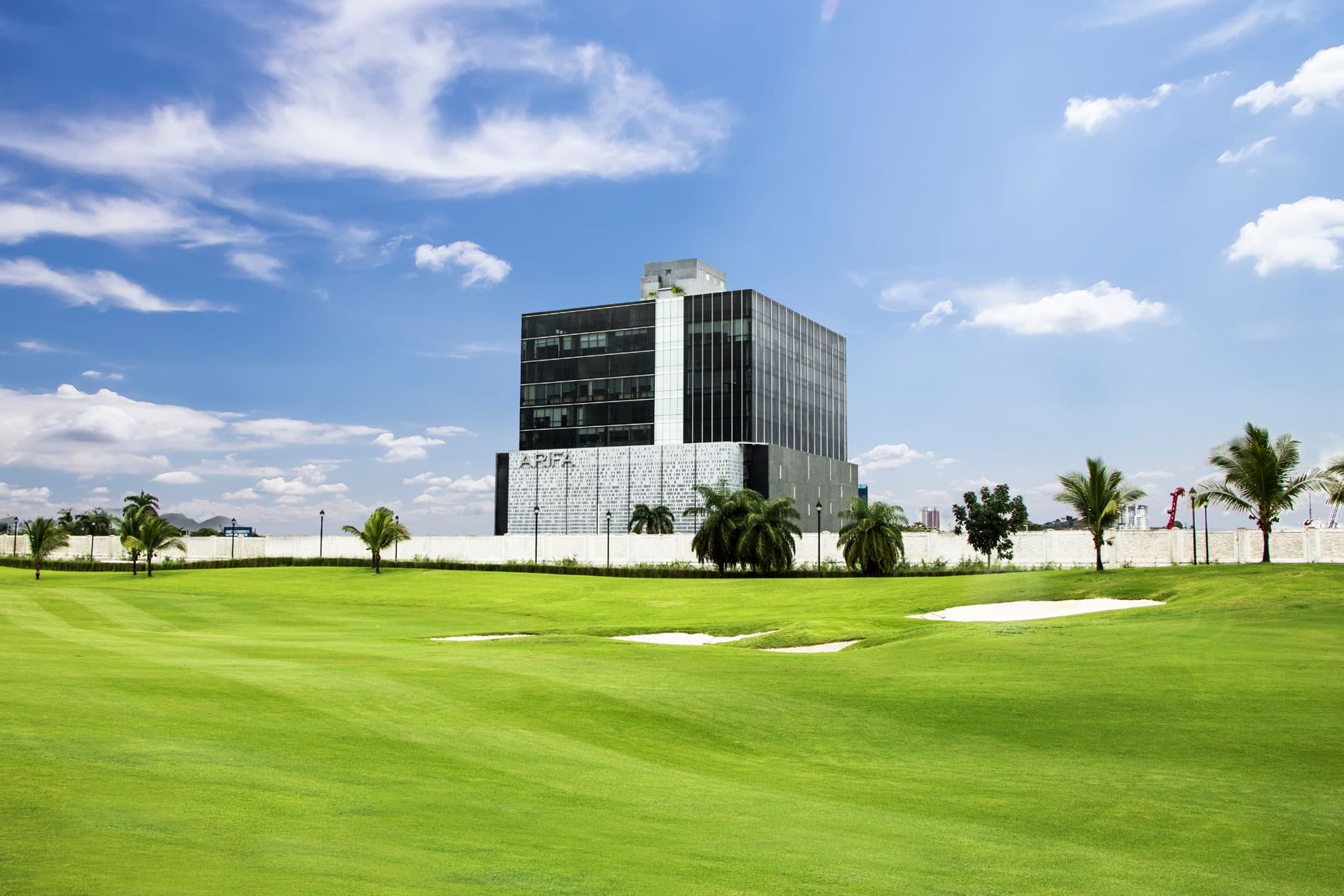 PH Arifa glass office tower framed by palms and the golf course fairway