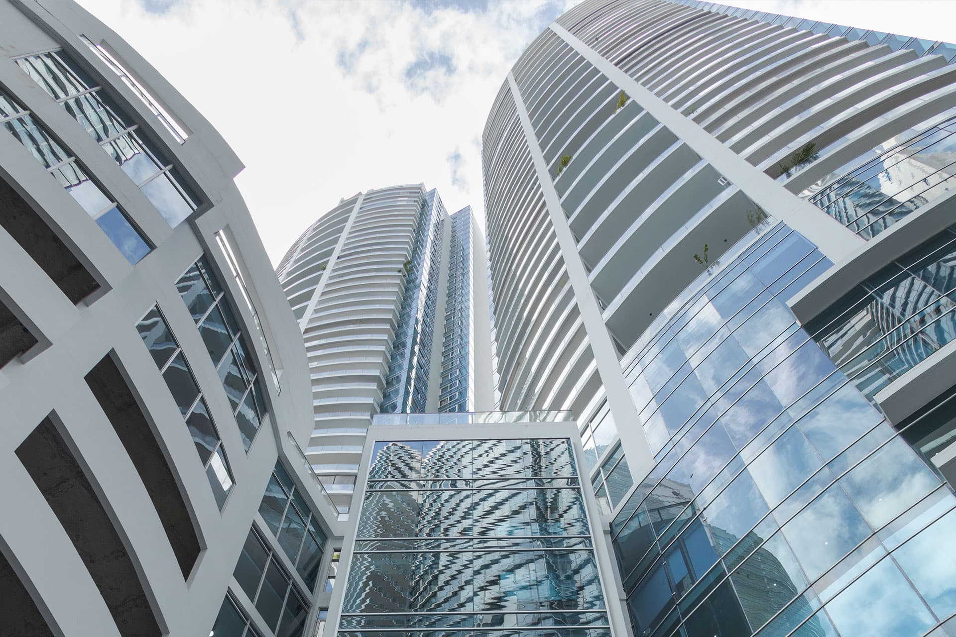 Pacific Village towers seen from below with curved balconies and glass facades