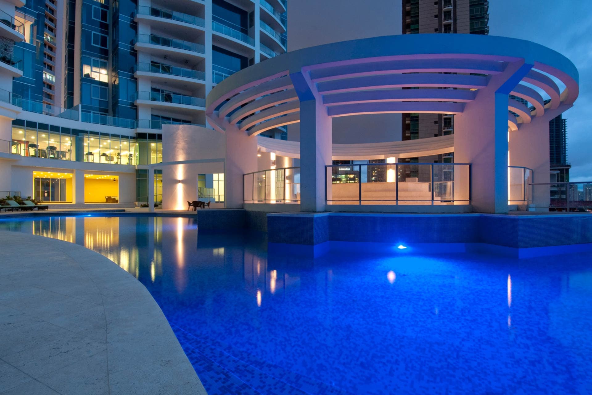 Illuminated pool and circular pergola at Pacific Village at dusk