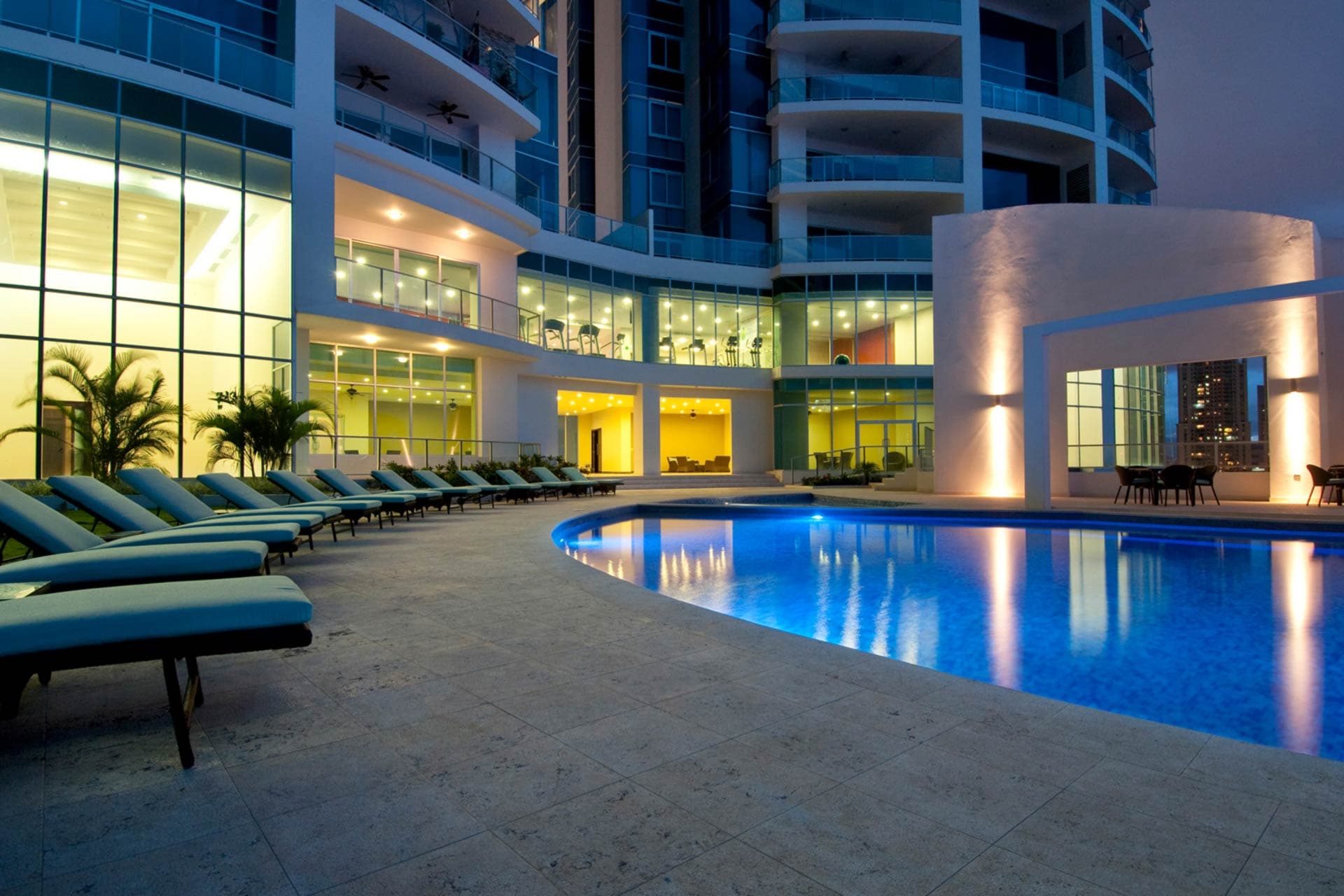 Pool deck with loungers at Pacific Village at night
