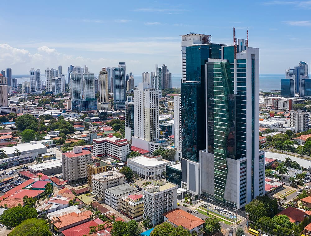 Aerial view of the Fortune Plaza tower above Obarrio with the Panama City skyline and bay behind
