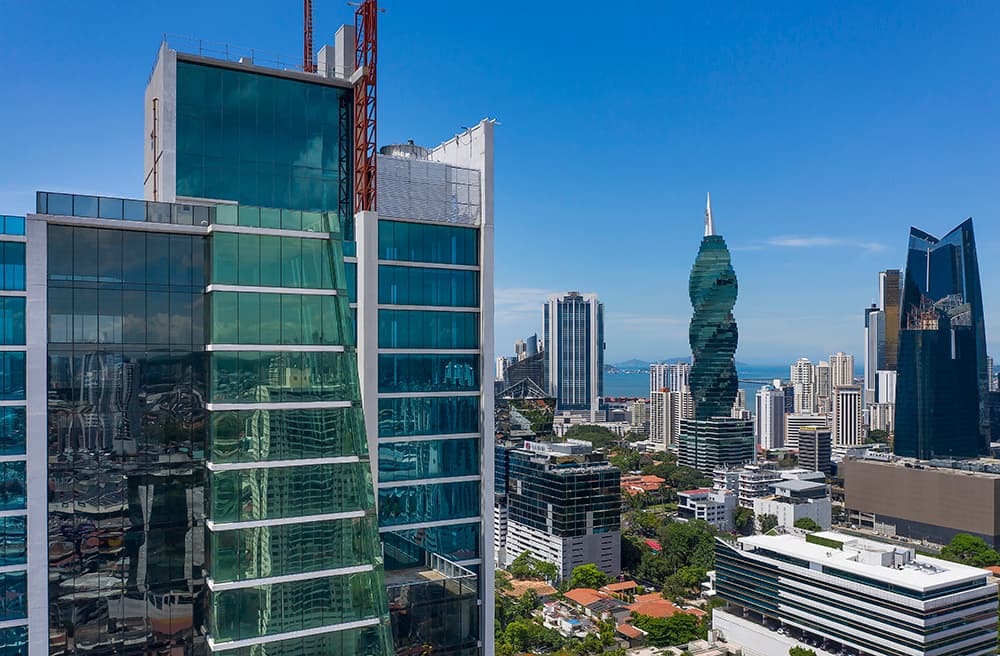 Green glass facade of Fortune Plaza with the Obarrio skyline and F&F Tower behind