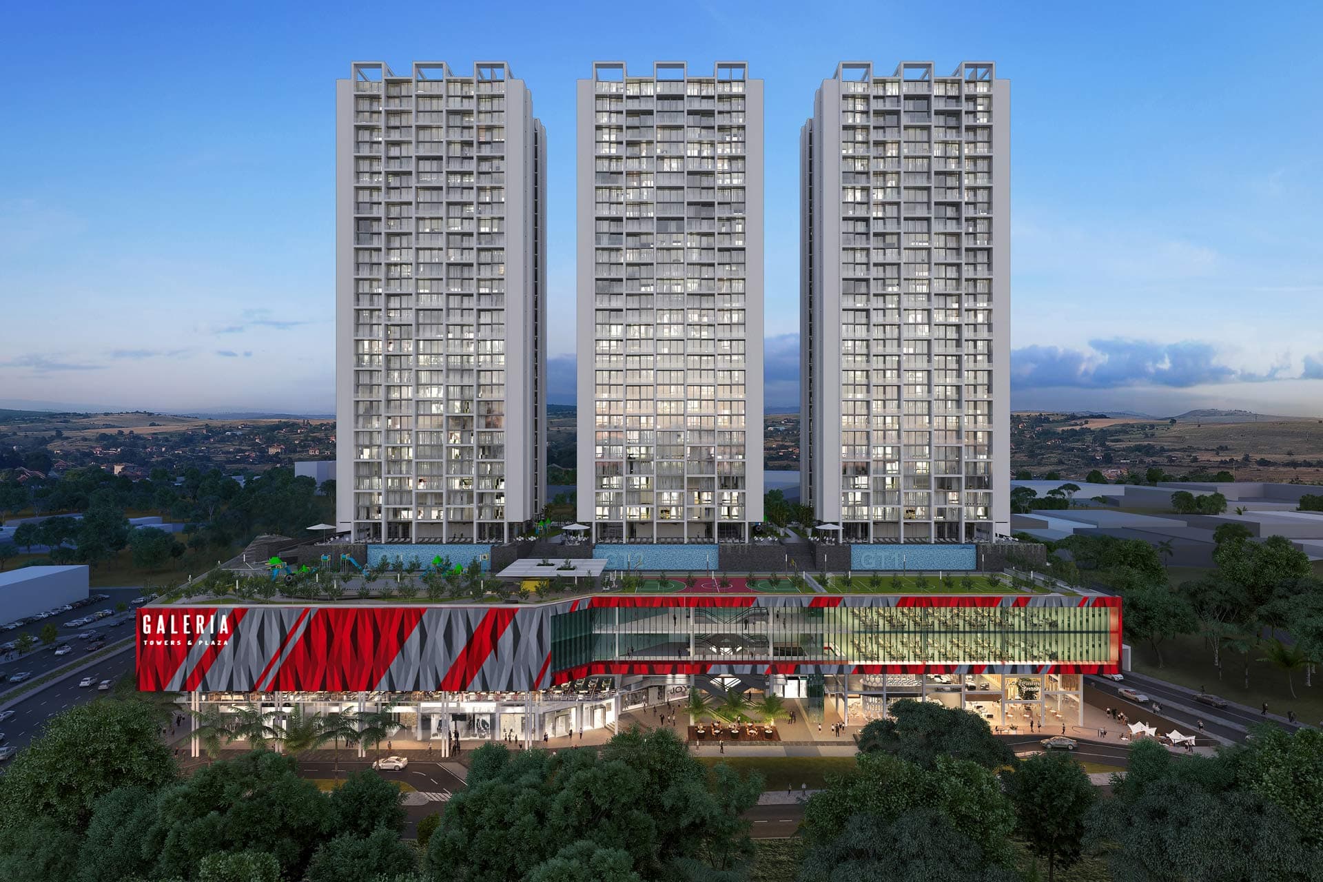 The three residential towers of Galería Towers above the commercial plaza at dusk