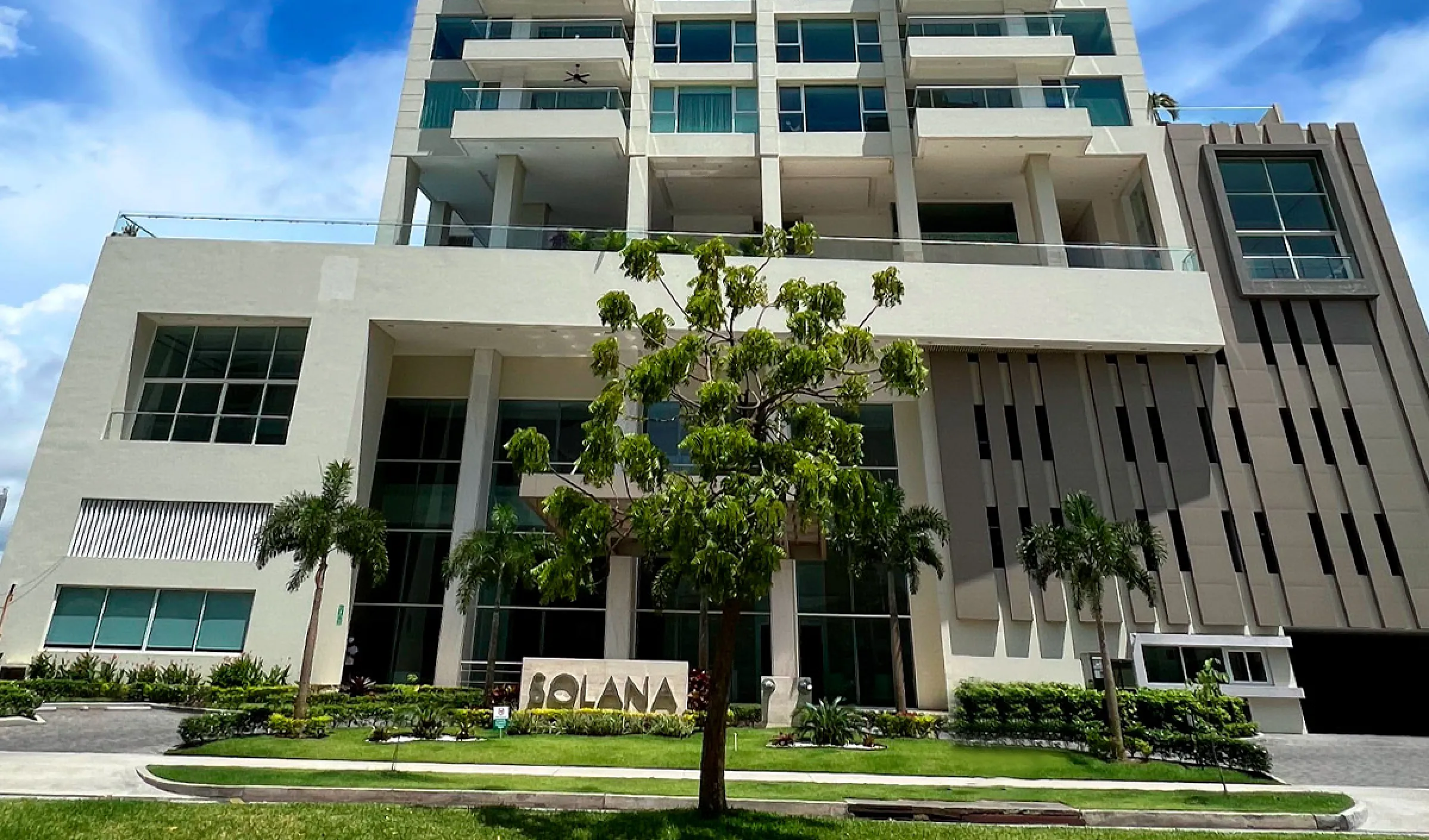 Entrance and lower facade of the Solana tower with its name sign and landscaping