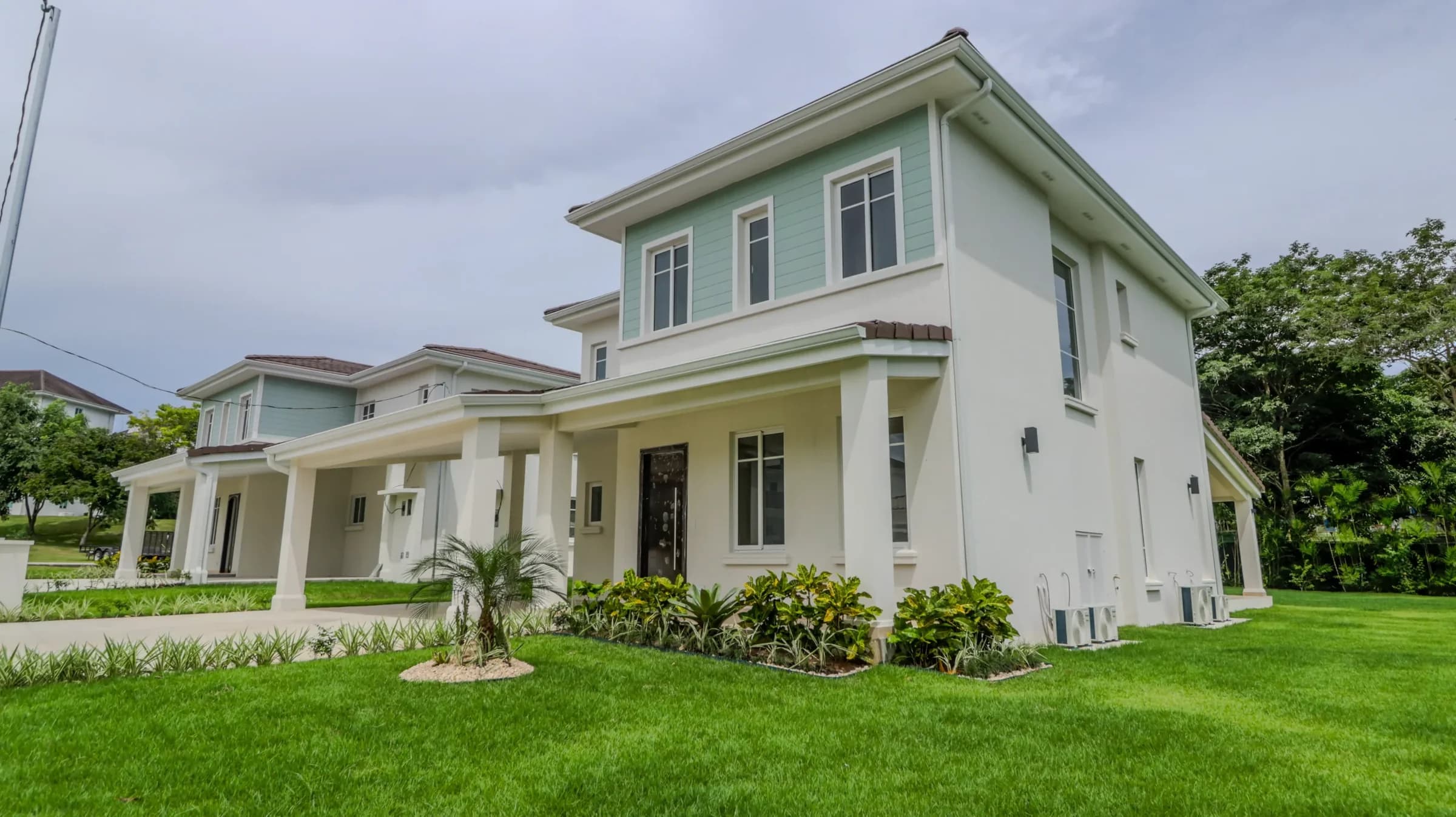 Completed two-storey white Veranera beach house with lawn and tropical garden at Bijao, Panama