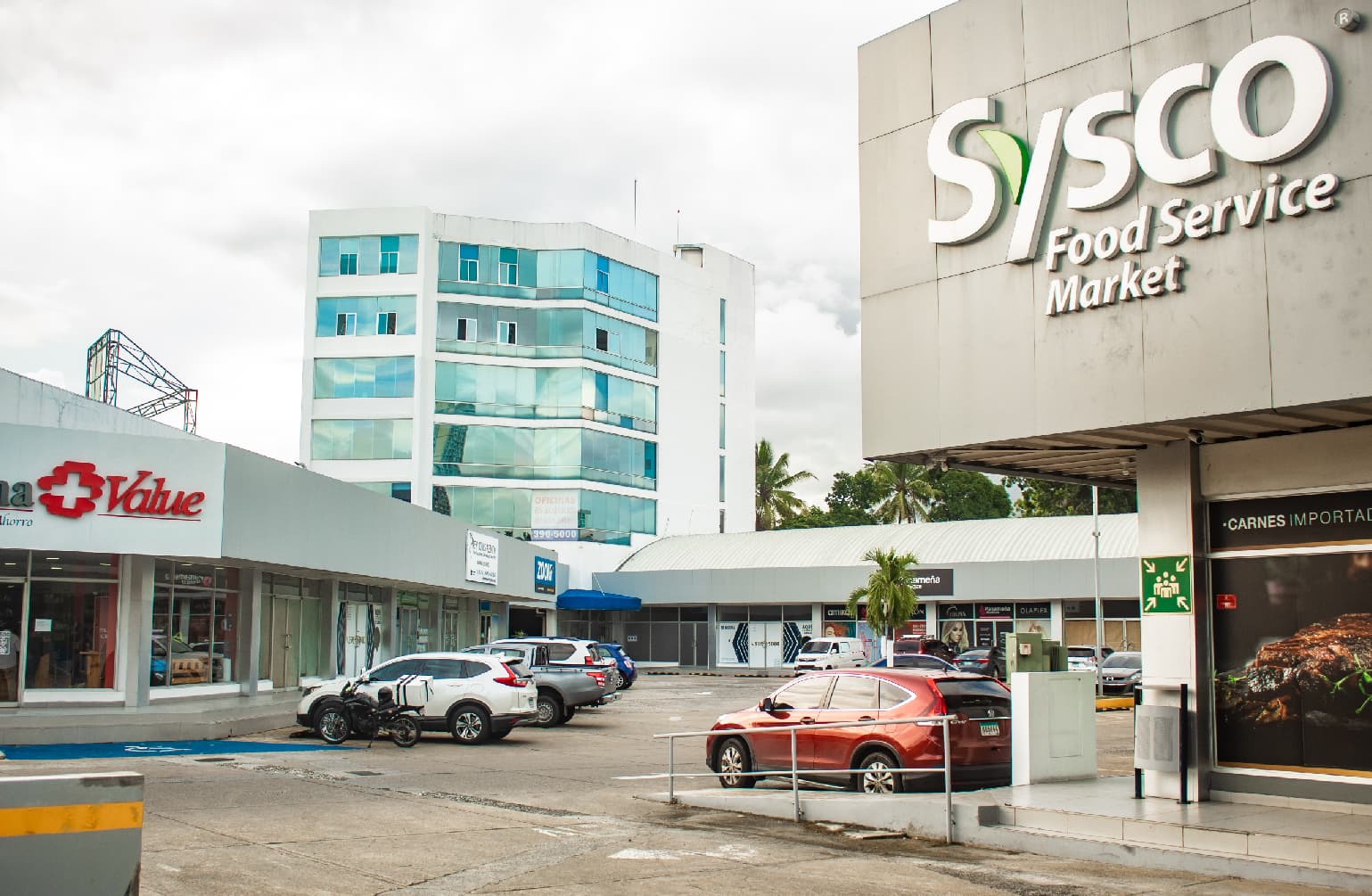 Parking court and storefronts of Centro del Este with the office building behind