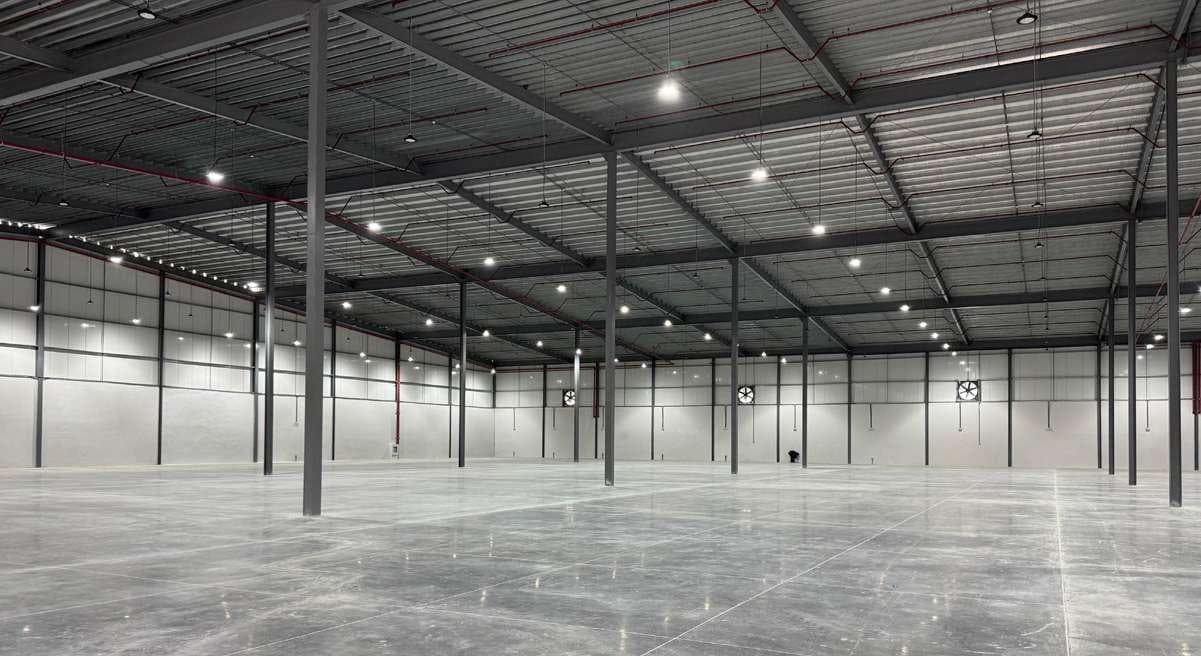 Interior of an empty warehouse at Parque Logístico Cocosolito with high ceilings and steel columns