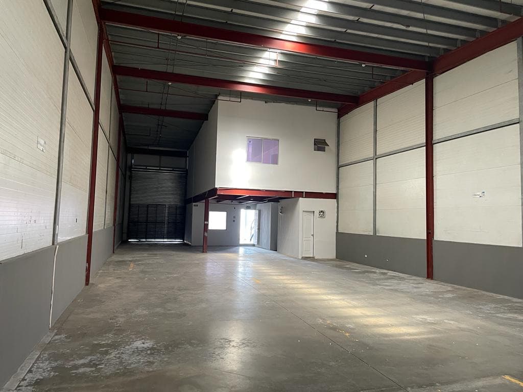 Photograph of an empty warehouse unit with its mezzanine office and roll-up door at Tocumen Office Storage, Tocumen, Panama City