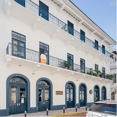 Street facade of El Colegio II with arched ground-floor doors and wrought-iron balconies, Casco Viejo, Panama City