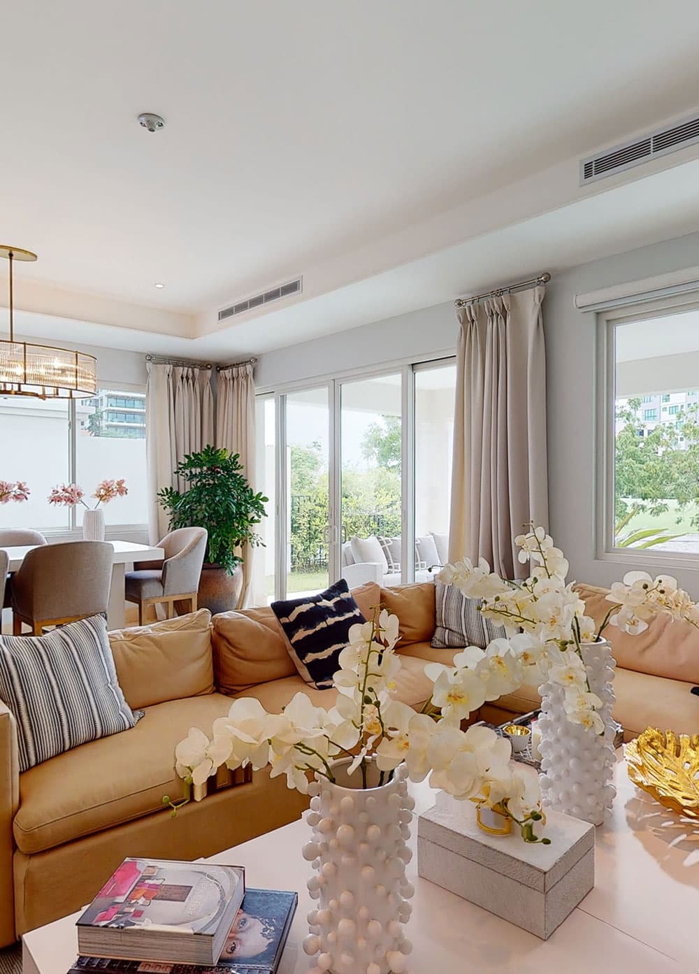 Living area with garden-view windows and orchid centrepiece in a home at The Crescent, Santa Maria