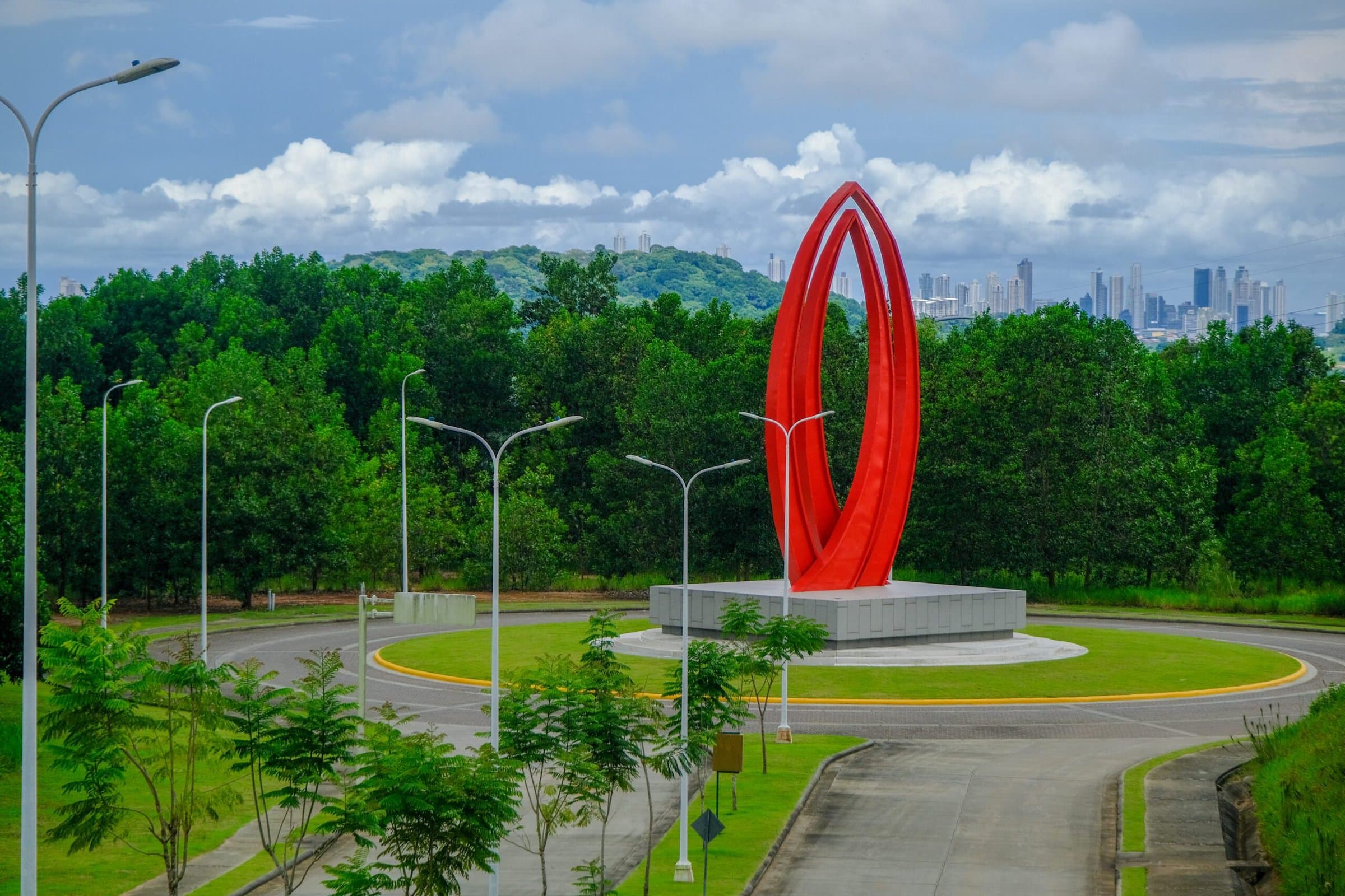 Green City entrance roundabout with red sculpture and forested hills