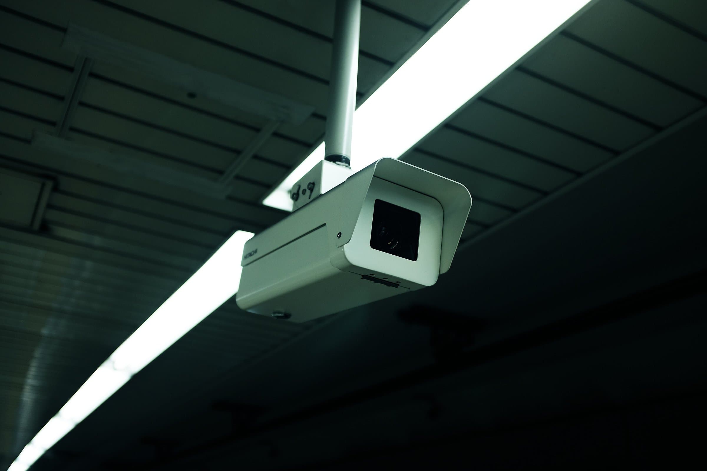 Surveillance camera mounted on a ceiling beside a strip light