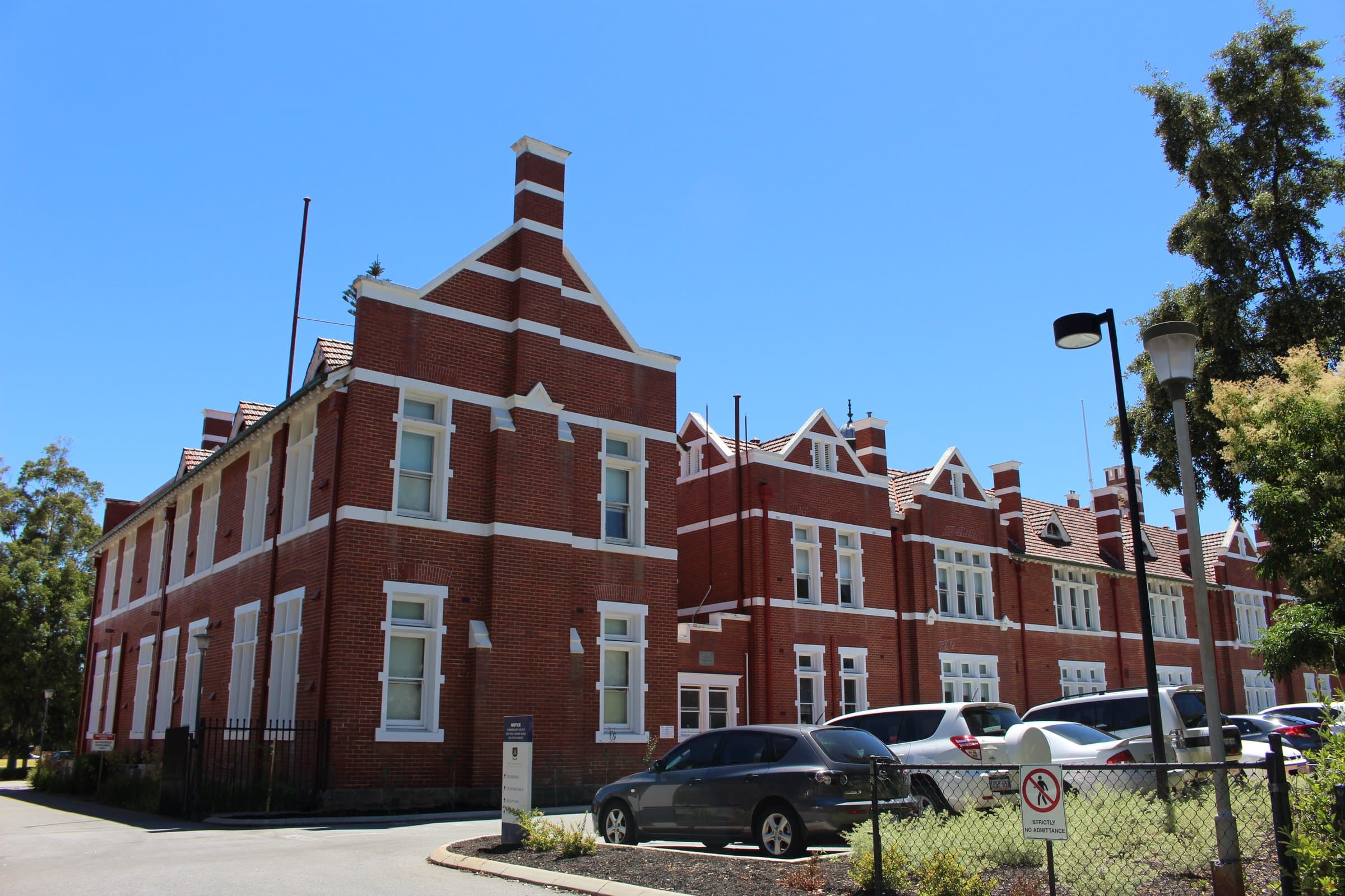 Red-brick school building with white gables under a clear blue sky