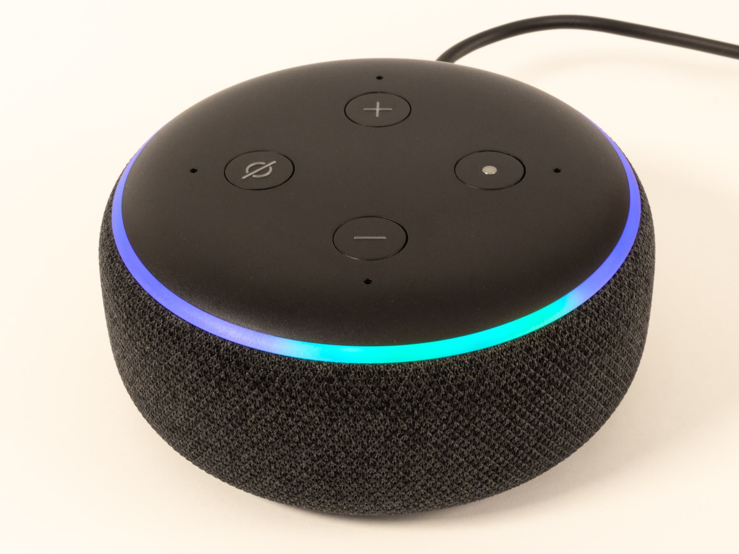 Smart speaker with an illuminated blue light ring on a white surface