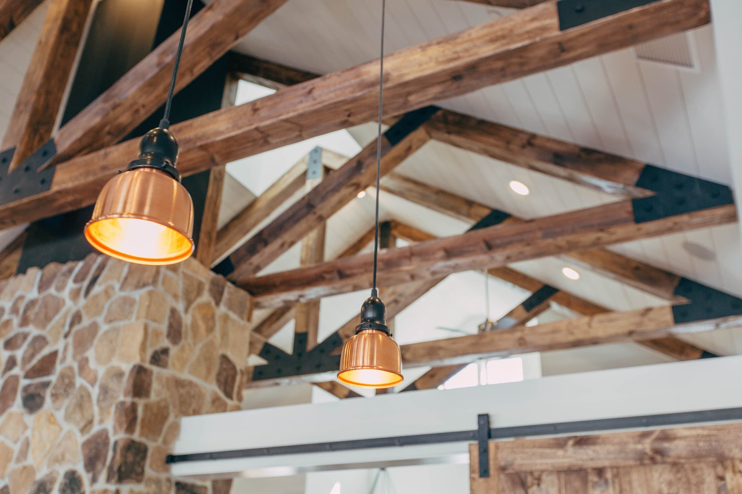 High ceiling with exposed timber beams and copper pendant lamps in a modern house
