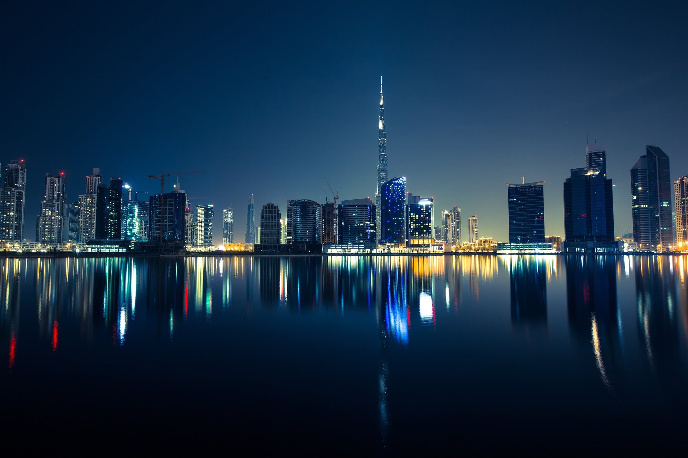City skyline of high-rise towers at night reflected in calm water