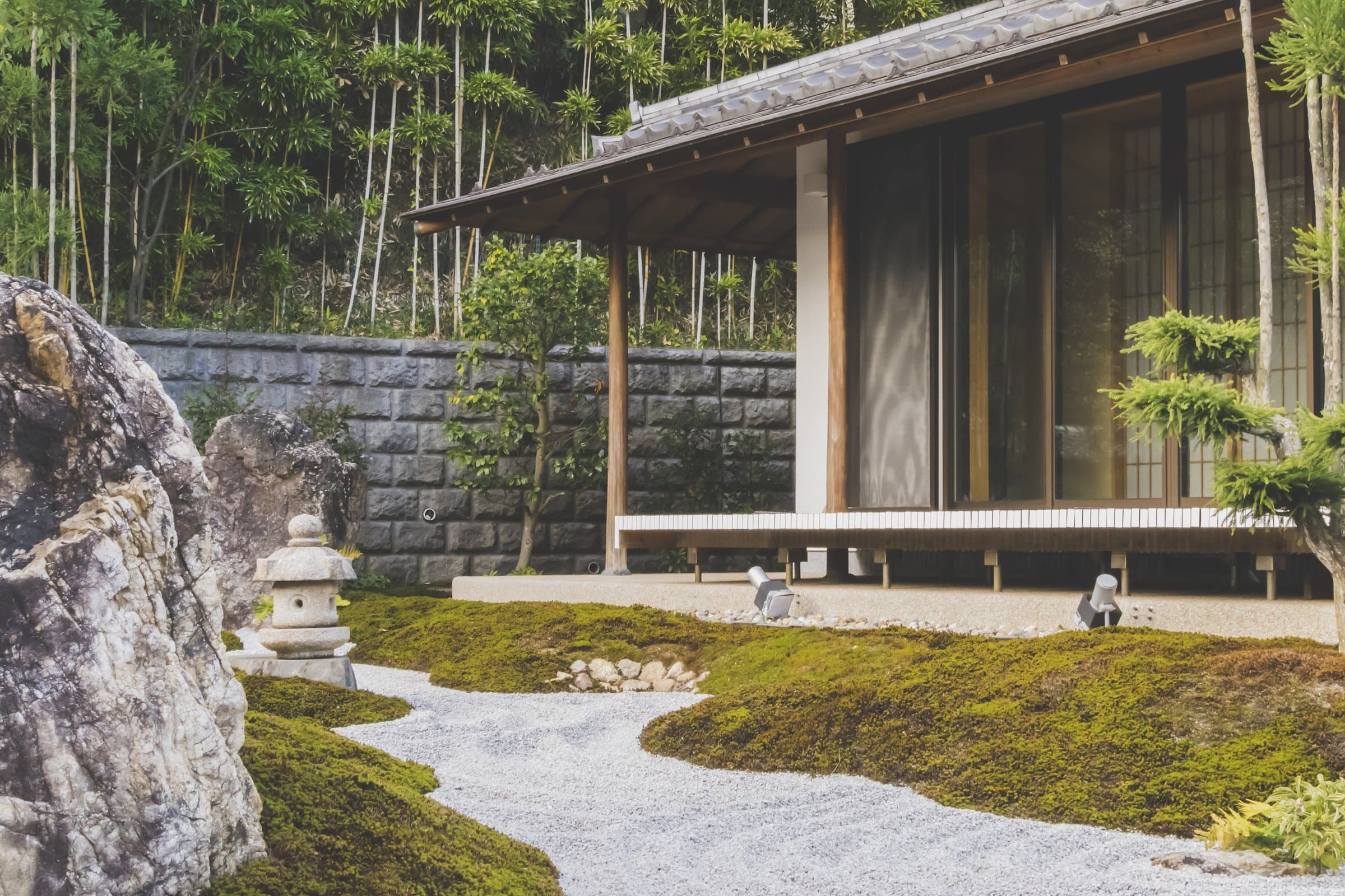 House with a wooden veranda opening onto a private garden of raked gravel, moss, rocks and stone lanterns