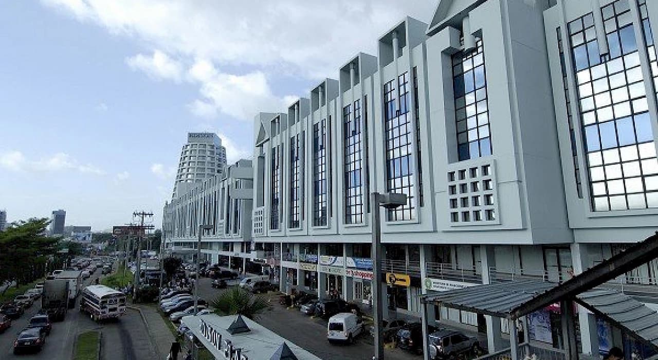 Photograph of the Edison Plaza storefront arcade along the access road, with its cylindrical tower behind, Edison Park, Panama City