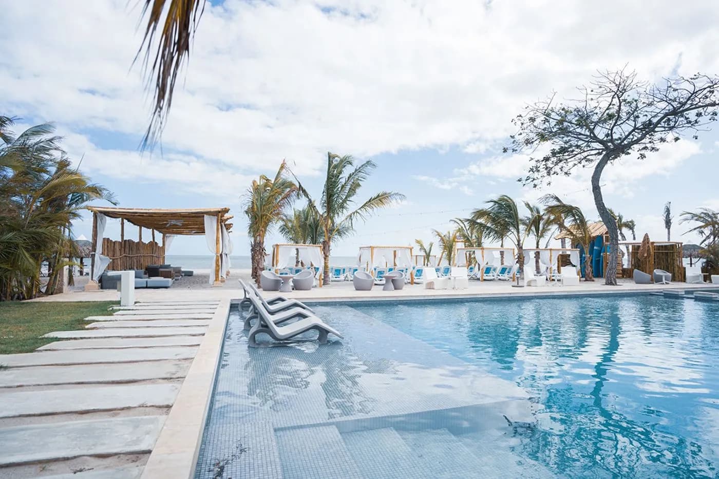 Beach club pool with loungers and palms at The Tides, Playa Caracol