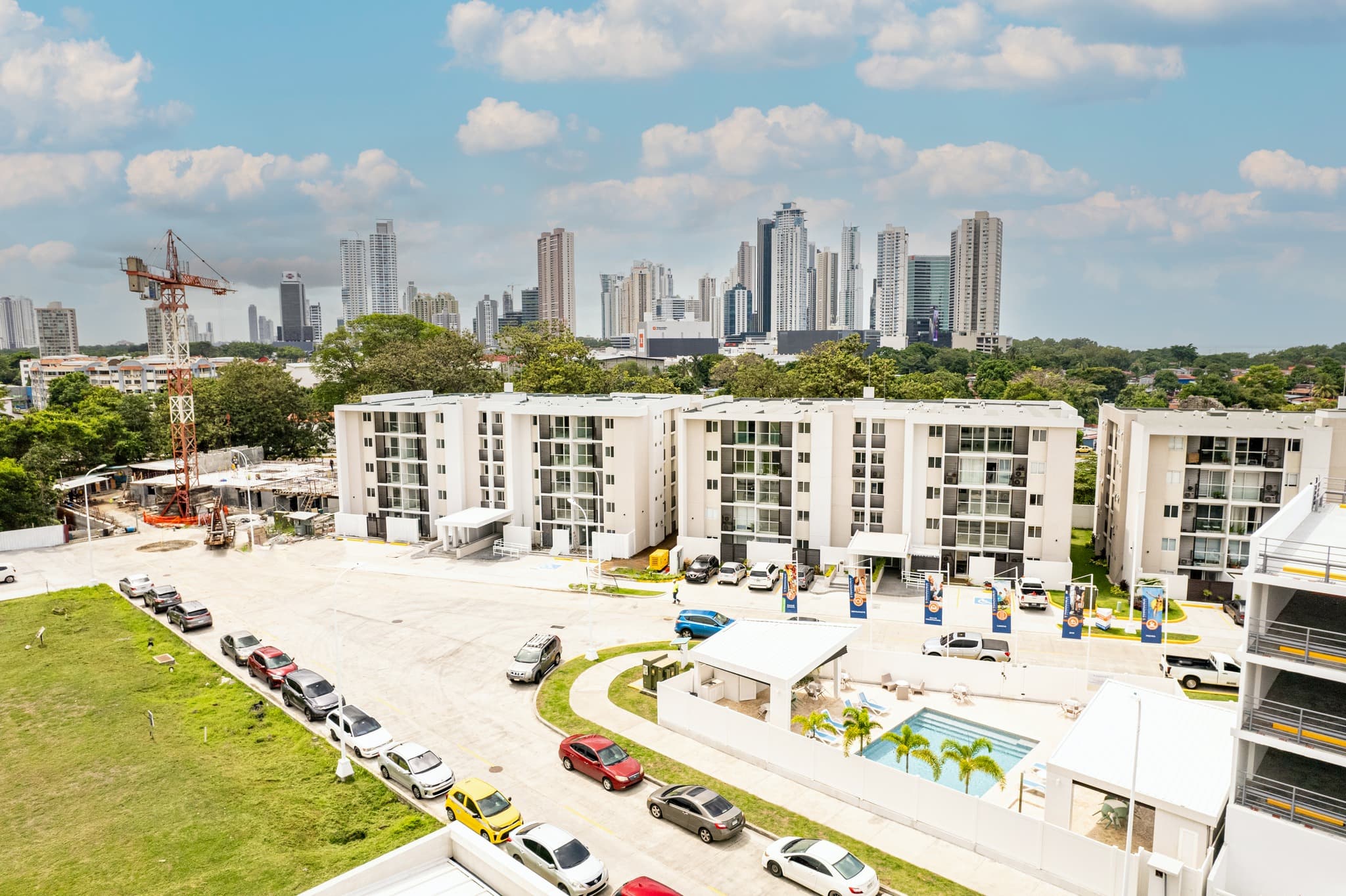 Aerial view of the low-rise Panama Viejo Residences buildings and pool with the Panama City skyline behind