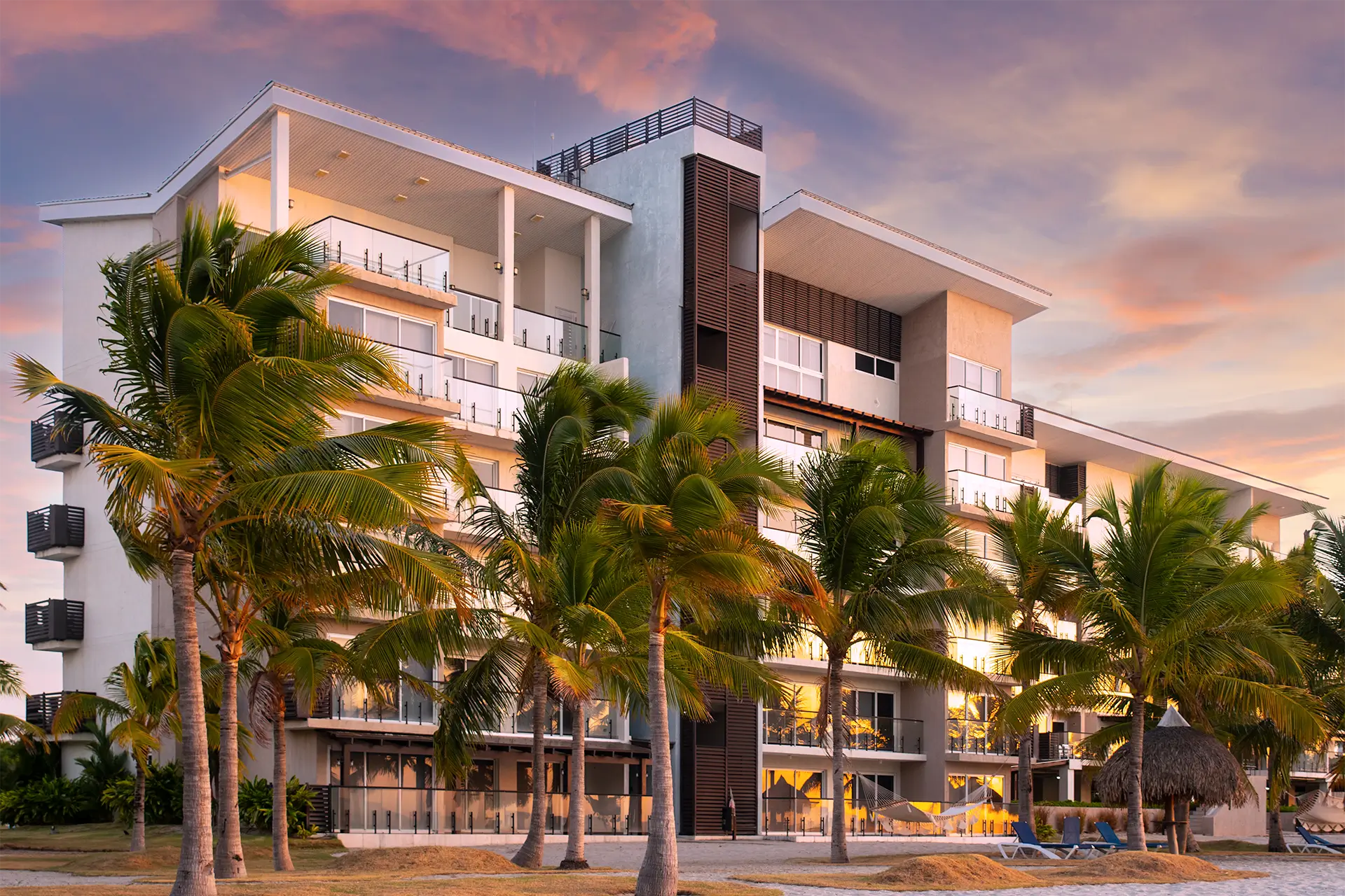 Olas del Mar apartment building among palm trees at sunset in Playa Caracol
